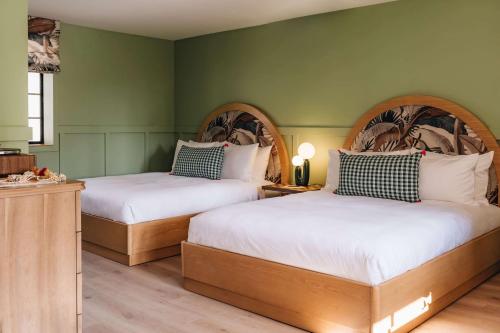 two beds in a room with green walls at Wayfinder Waikiki - Voted Top 10 Best Hotels in Hawaii! in Honolulu