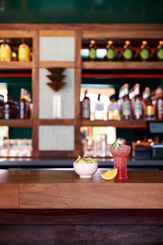 a counter in a bar with a bowl of food and a drink at Wayfinder Waikiki - Voted Top 10 Best Hotels in Hawaii! in Honolulu