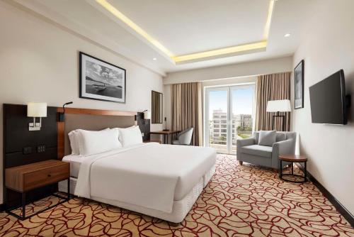 a bedroom with a large white bed and a chair at Radisson Hotel Muscat Panorama in Muscat