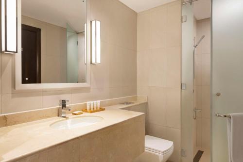 a bathroom with a sink and a toilet and a mirror at Radisson Hotel Muscat Panorama in Muscat