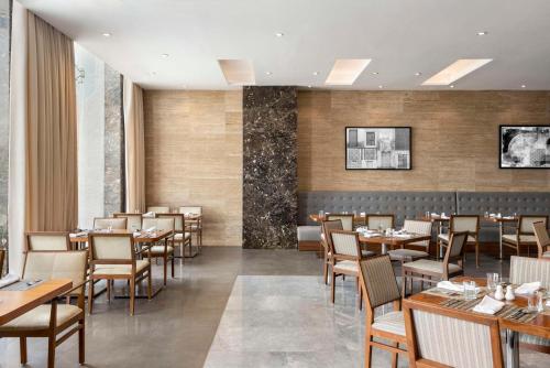 a dining room with wooden tables and chairs at Radisson Hotel Muscat Panorama in Muscat