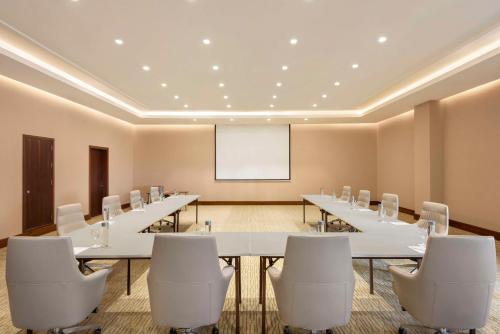a conference room with a long table and white chairs at Radisson Hotel Muscat Panorama in Muscat