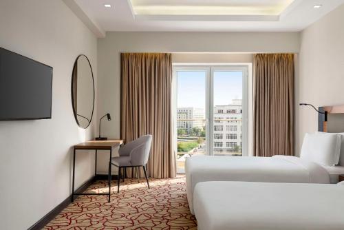 a hotel room with two beds and a window at Radisson Hotel Muscat Panorama in Muscat