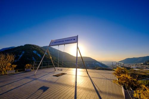 a sign on the roof of a building with the sun setting at 阿蘇CANYON TERRACE＆LODGE in Kurogawa