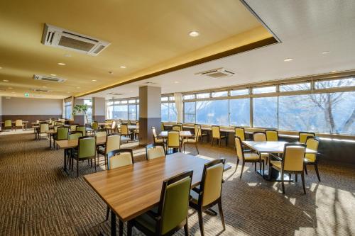 a dining room with tables and chairs and windows at 阿蘇CANYON TERRACE＆LODGE in Kurogawa