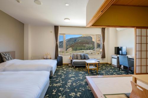 una camera d'albergo con due letti e una finestra di 阿蘇CANYON TERRACE＆LODGE a Kurokawa Onsen