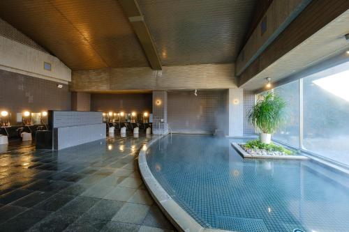 a large swimming pool in a building with a pool at 阿蘇CANYON TERRACE＆LODGE in Kurogawa
