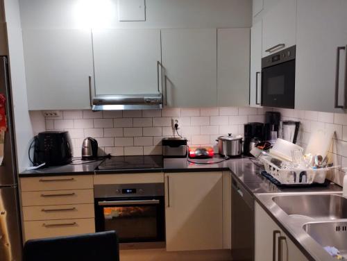 a kitchen with white cabinets and a stove top oven at Jahminatu`s Apartment in Södertälje