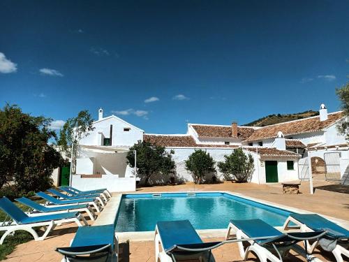 a swimming pool with lounge chairs and a house at Cortijo Alzamigaja in Archidona