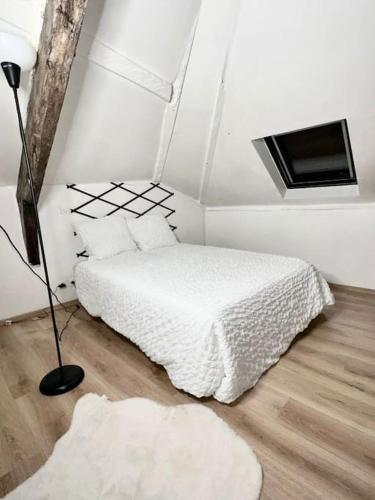- une chambre blanche avec un lit et une lampe dans l'établissement Duplex chaleureux, à Corbeil-Essonnes