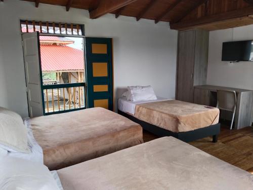a room with two beds and a window at Colina del Sol Hotel Hacienda in Quimbaya