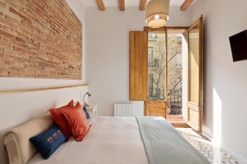バルセロナにあるPoble Sec Charming Apartmentのレンガの壁、ベッド付きのベッドルーム1室