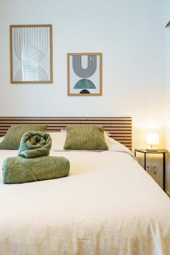 - un lit blanc avec 2 serviettes vertes dans l'établissement Studio Ensoleillé 2pers wifi, à Saint-Quentin