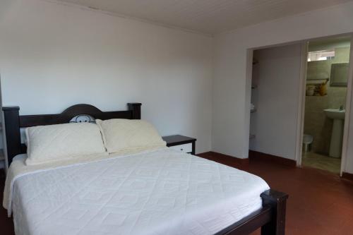 a bedroom with a bed and a bathroom with a sink at Colina del Sol Hotel Hacienda in Quimbaya