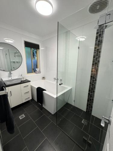a bathroom with a shower and a tub and a sink at Belle in Bowral in Bowral