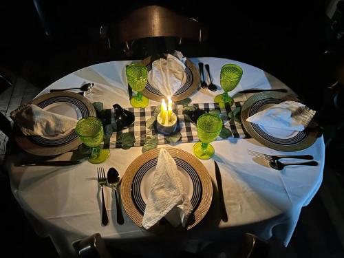 a table with plates and glasses and a candle on it at Hermosa Cabaña de campo Selah in Tabio