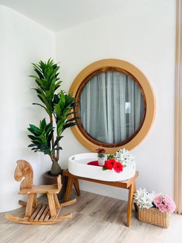 a round mirror above a table with flowers on it at Villa De Phawa in Samut Songkhram