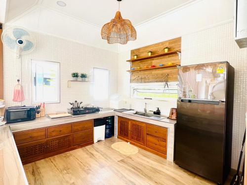 a kitchen with wooden cabinets and a black refrigerator at Villa De Phawa in Samut Songkhram
