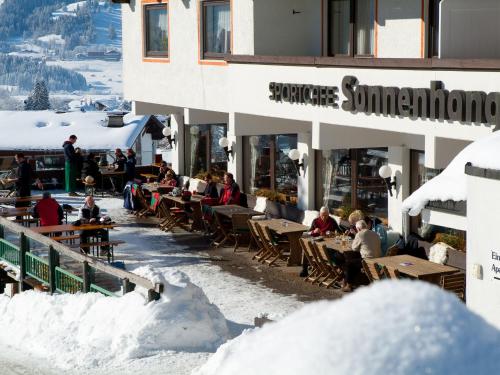 a group of people sitting outside of a building in the snow at Appartementhaus Sonnenhang in Ehrwald