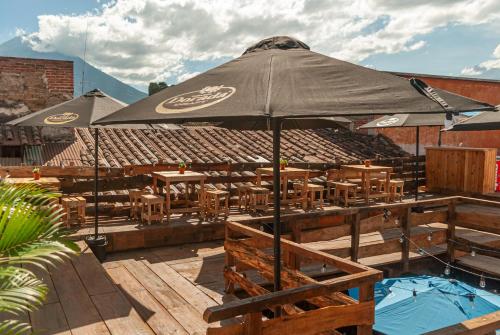 a patio with tables and chairs and an umbrella at Kamazoztz Hostel and Travel in Antigua Guatemala