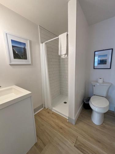 a white bathroom with a toilet and a shower at San Dune Inn in Manzanita