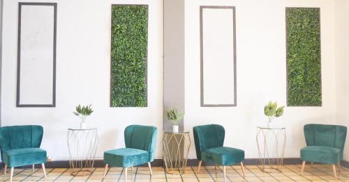 uma sala de espera com cadeiras verdes e espelhos em Kali Hotel em Santa Ana