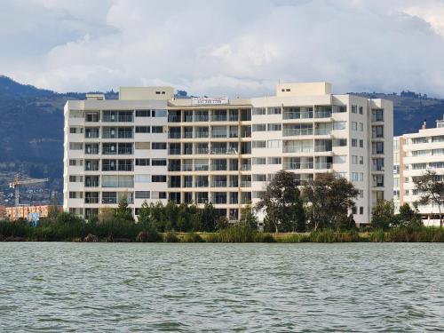 a large white building next to a body of water at Apartamento en Paipa frente al lago in Paipa
