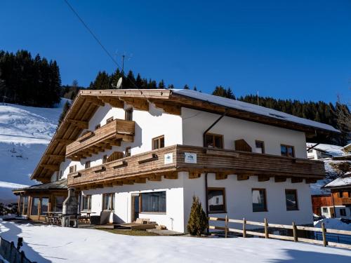 a building with a wooden roof in the snow at Mooshäusl Large in Hopfgarten im Brixental