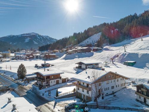 a village covered in snow with the sun in the background at Mooshäusl in Hopfgarten im Brixental
