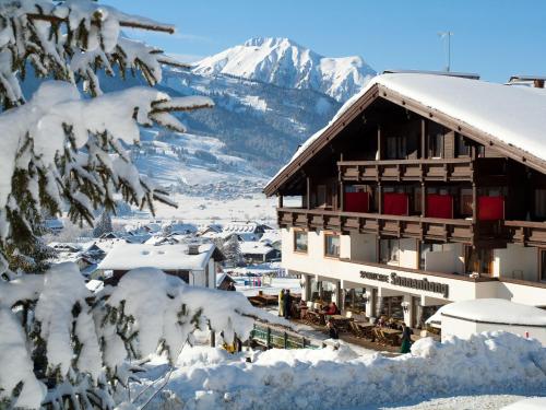 a snow covered building with a mountain in the background at Appartementhaus Sonnenhang in Ehrwald