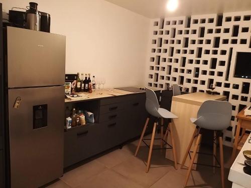 eine Küche mit einem Kühlschrank und einer Theke mit Barhockern in der Unterkunft duplex moderne direct aéroport in Les Abymes