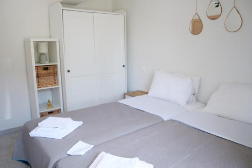 a white bedroom with a bed with white sheets and towels at Aelia Summer House in Samos