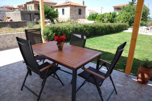 a wooden table with four chairs and a vase of flowers at Aelia Summer House in Samos