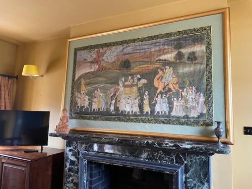 a painting above a fireplace in a living room at Llanerchydol Hall Suites in Welshpool