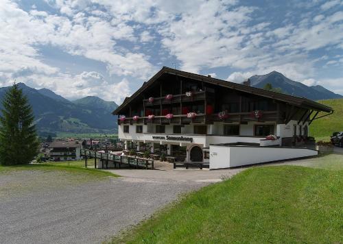 a building on a hill with mountains in the background at Appartementhaus Sonnenhang in Ehrwald