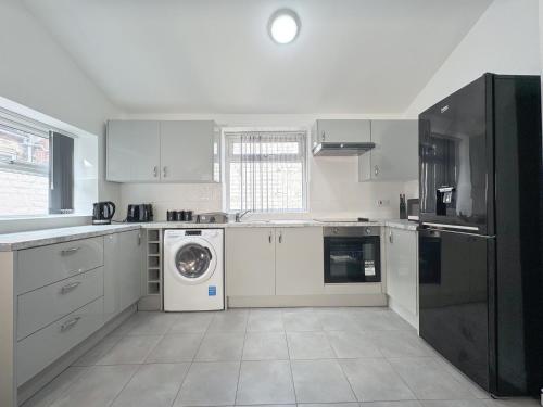 a kitchen with white cabinets and a washer and dryer at Relax @ Southfield in Middlesbrough