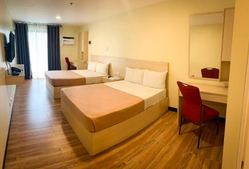 una habitación de hotel con 2 camas y una silla roja en Olive Town Center and Hotel en Baguio