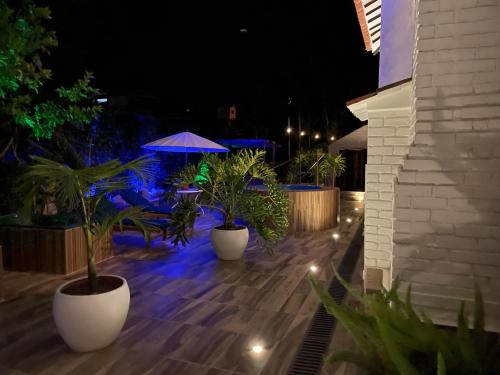 un patio con macetas y sombrilla por la noche en Bombon Hotel, en Villa de Leyva