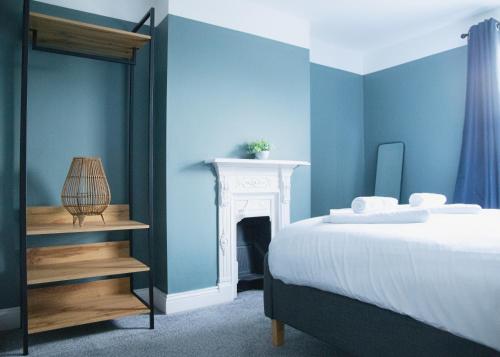 ein blaues Schlafzimmer mit einem Bett und einem Kamin in der Unterkunft Stylish 3x bed house in Soham in Soham