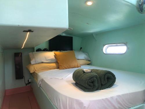 - une chambre avec un lit et une serviette dans l'établissement Velero Maverick hospedagem flutuante Centro Historico, à Parati