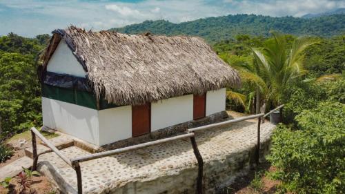uma pequena casa com um telhado de palha numa colina em Mirador Dentro del Parque Tayrona em El Zaino