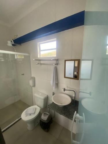 a bathroom with a white toilet and a sink at Pirai Hotel Fazenda in Piraí