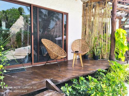 a wooden deck with two chairs and a table at Arte Sano Hotel Only Adults - Near Beach in Holbox Island