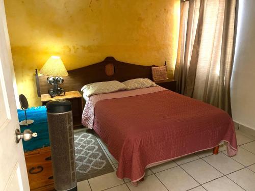 1 dormitorio con 1 cama y 1 mesa con lámpara en Casa Gaviotas Art cozy 2 bed house with art studio close to downtown en La Paz