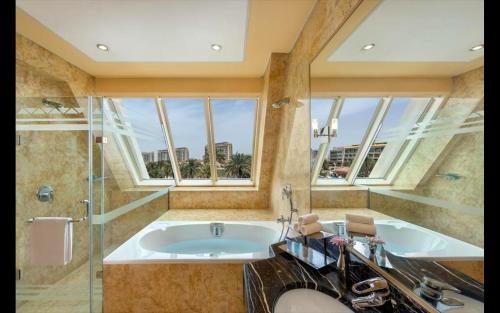 阿布達比的住宿－Al Raha Beach Hotel - Deluxe Gulf Room SGL - UAE，带浴缸和窗户的大浴室