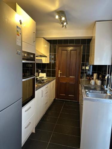 cocina con armarios blancos y puerta de madera en Leavesden Residence - Central - Cosy - Harry Potter, en Leavesden Green