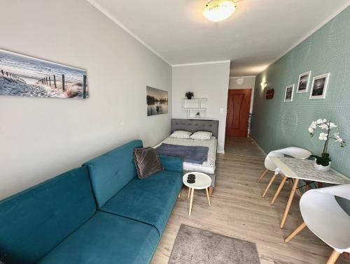 a living room with a blue couch and a bed at Pod Papugami - Komfortowe pokoje z widokiem na rzekę in Łeba