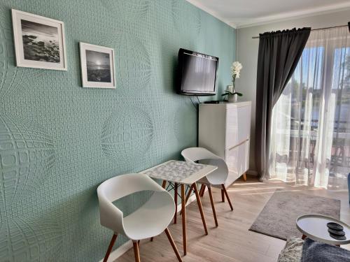 a room with four chairs and a table and a tv at Pod Papugami - Komfortowe pokoje z widokiem na rzekę in Łeba