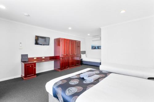 a bedroom with a bed and a desk and a tv at Hilton Motel in Port Lincoln