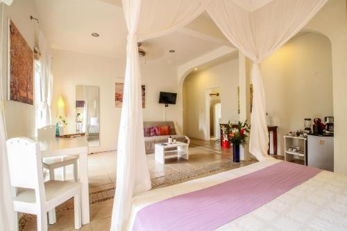 1 dormitorio con cama con dosel y sala de estar. en Villas Geminis Boutique Condohotel, en Tulum